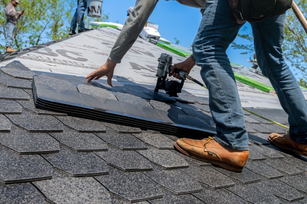 Roofer using a nail gun to install shingles on a residential roof