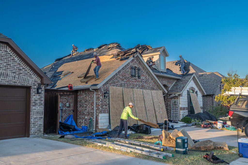 Roofing crew replacing the roof on a brick house