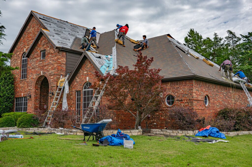 Roofers laying new shingles on a brick home